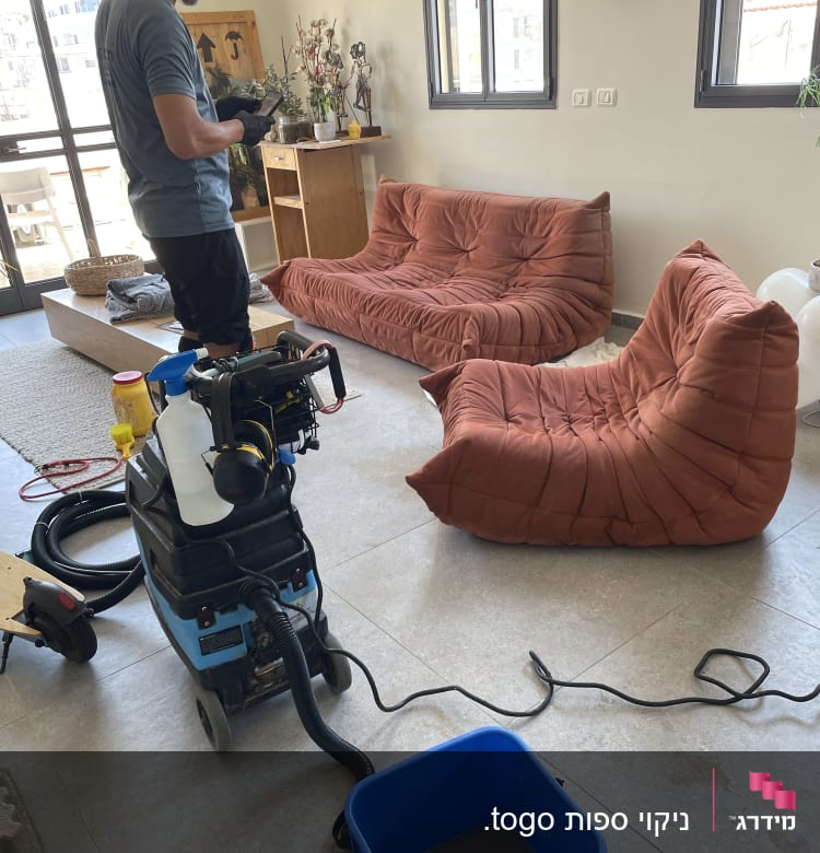 אדם מנקה ספות עם מכונת ניקוי ושואב אבק